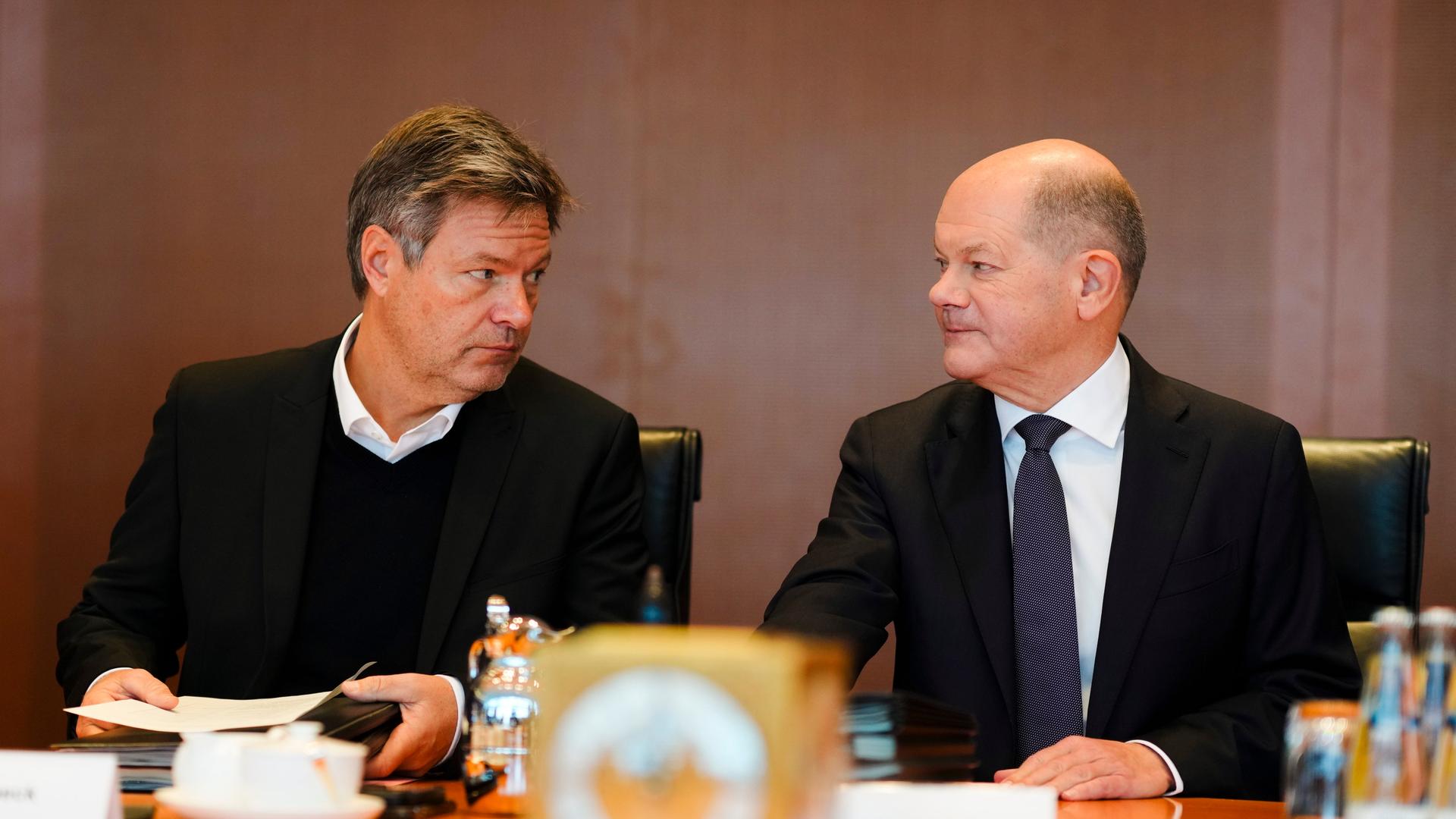 Vizekanzler Robert Habeck (Grüne) und Kanzler Olaf Scholz sitzen am selben Tisch und schauen sich gegenseitig in die Augen.