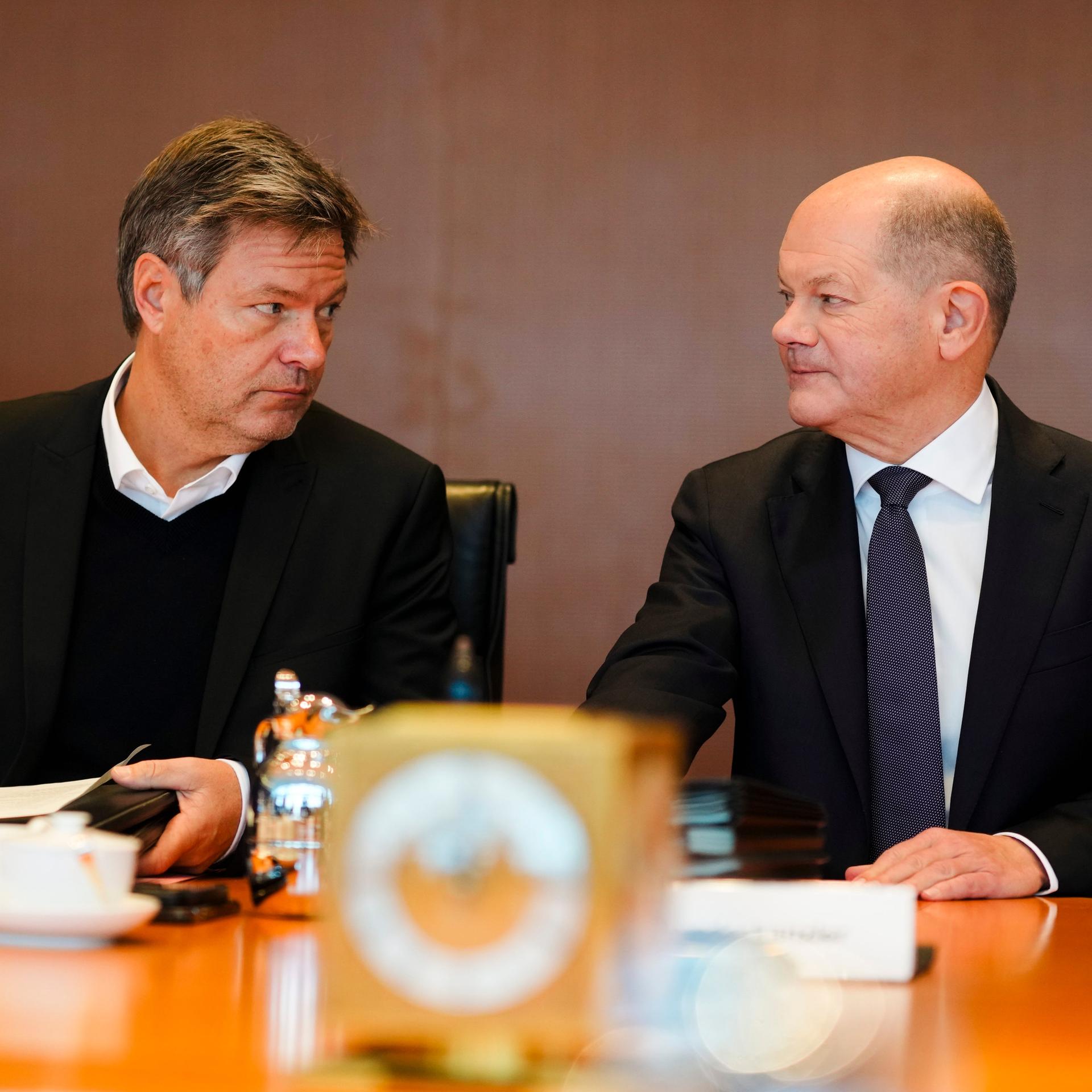 Vizekanzler Robert Habeck (Grüne) und Kanzler Olaf Scholz sitzen am selben Tisch und schauen sich gegenseitig in die Augen.