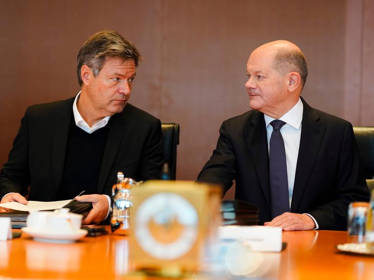 Vizekanzler Robert Habeck (Grüne) und Kanzler Olaf Scholz sitzen am selben Tisch und schauen sich gegenseitig in die Augen.