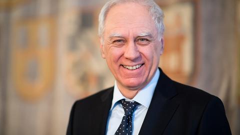Bruno Jonas lacht in die Kamera, ein älterer Mann mit weißem Haar im schwarzen Anzug und gepunkteter Krawatte.
