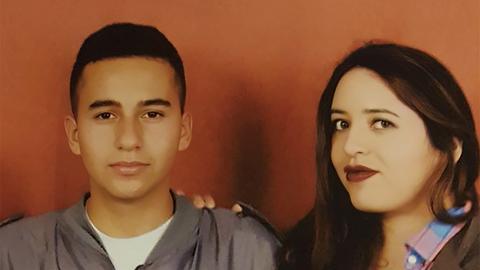 Porträt einer Frau mit ihrem Sohn vor einer orangefarbenen Wand