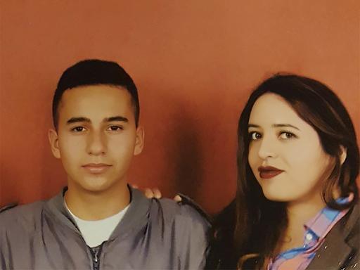 Porträt einer Frau mit ihrem Sohn vor einer orangefarbenen Wand