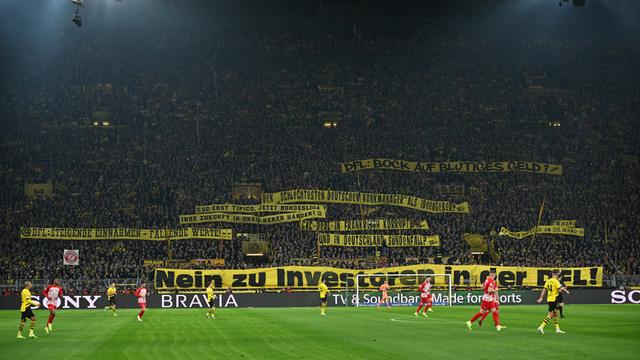 Blick auf die Tribüne in Dortmund. Auf einem BVB-Banner steht schwarz auf gelb: "Nein zu Investoren in der DFL!"