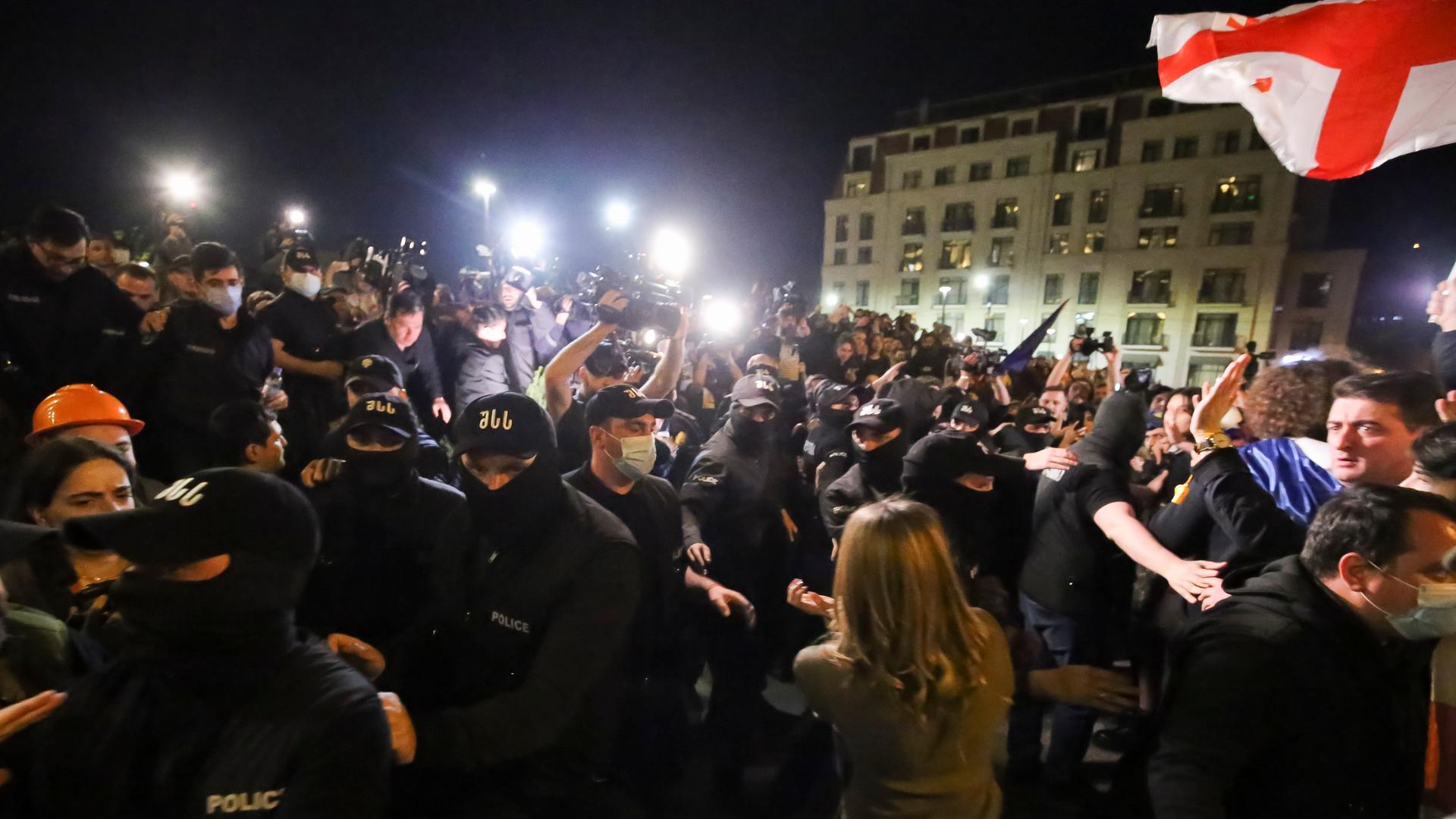 Vermummte Polizisten in Uniform versuchen, Demonstranten aufzuhalten, die vor dem Parlamentsgebäude in Tiflis versammelt haben. 
