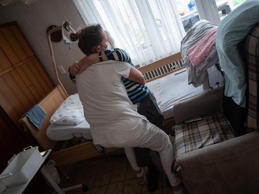 Anna Hahn (vorne), Pflegefachkraft, setzt während ihrer Schicht in der ambulanten Pflege eine Klientin vom Bett auf den Sessel. Am 12. Mai ist der Tag der Pflege.
