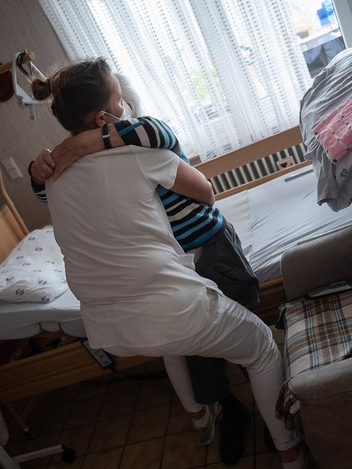 Anna Hahn (vorne), Pflegefachkraft, setzt während ihrer Schicht in der ambulanten Pflege eine Klientin vom Bett auf den Sessel. Am 12. Mai ist der Tag der Pflege.