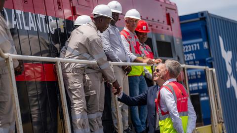 Der ehemalige US-Präsident Joe Biden (Mitte) begrüßt zusammen mit dem Betriebsleiter Nicolas Gregoir (rechts) Arbeiter während einer Besichtigung der Lobito Atlantic Railway im Hafen von Lobito am 4. Dezember 2024 in Angola.