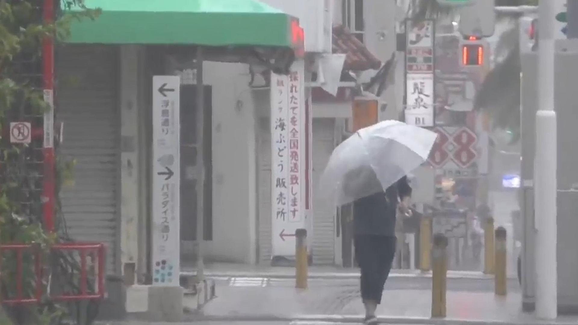 Eine Person läuft in der Stadt Naha in der japanischen Präfektur Okinawa mit einem Regenschirm. Eine Person läuft in der Stadt Naha in der japanischen Präfektur Okinawa mit einem Regenschirm.