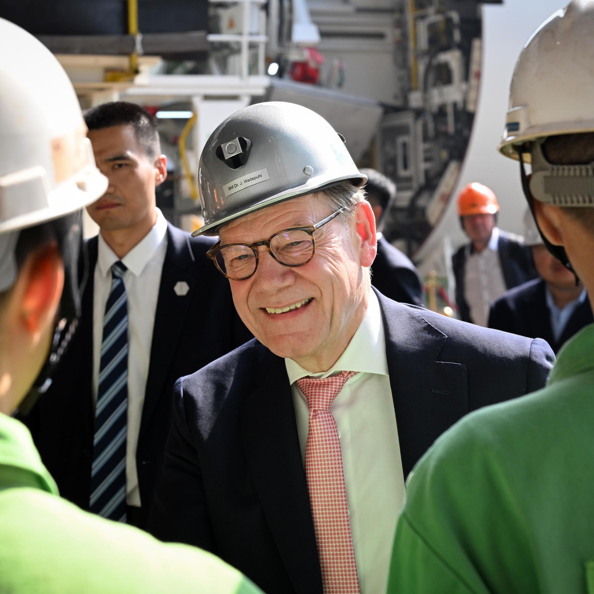 Guangdong: Bundesaußenminister Wadephul (M, CDU) besucht die Herrenknecht AG. Zwei Mitarbeiter sind stehen vor ihm und sind von hinten zu sehen.