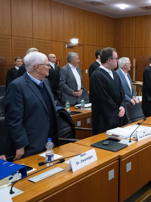 Die Angeklagten Theo Zwanziger (l), ehemaliger Präsident des Deutschen Fußball-Bundes (DFB), Wolfgang Niersbach (2.v.l., hinten), ehemaliger DFB-Präsident, und Horst R. Schmidt (r), ehemaliger DFB-Generalsekretär, erheben sich zum Auftakt des "Sommermärchen-Prozesses" im Verhandlungssaal am Landgericht Frankfurt.