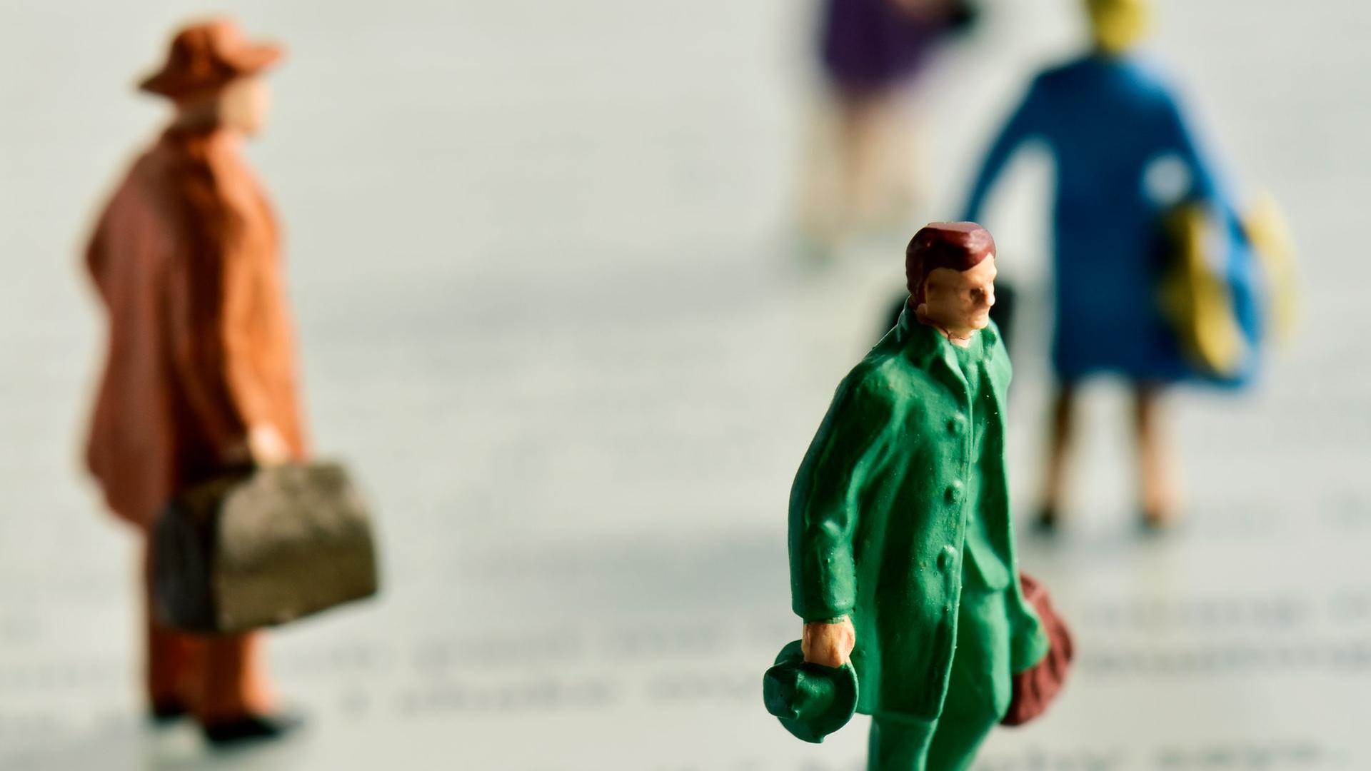Miniaturfiguren mit Koffern stehen auf einem e-Book-Reader.