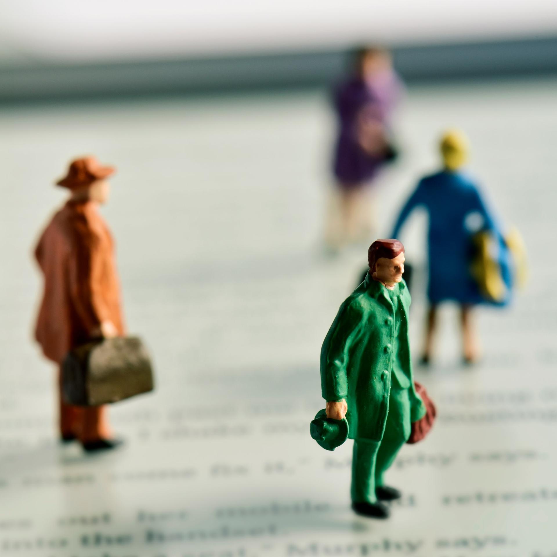 Miniaturfiguren mit Koffern stehen auf einem e-Book-Reader.