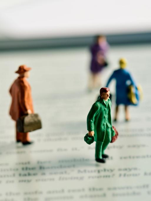 Miniaturfiguren mit Koffern stehen auf einem e-Book-Reader.
