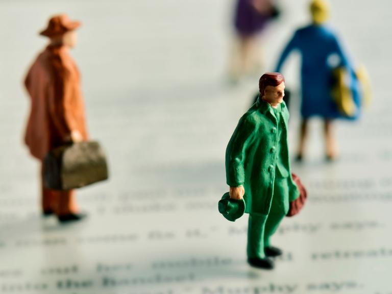 Miniaturfiguren mit Koffern stehen auf einem e-Book-Reader.