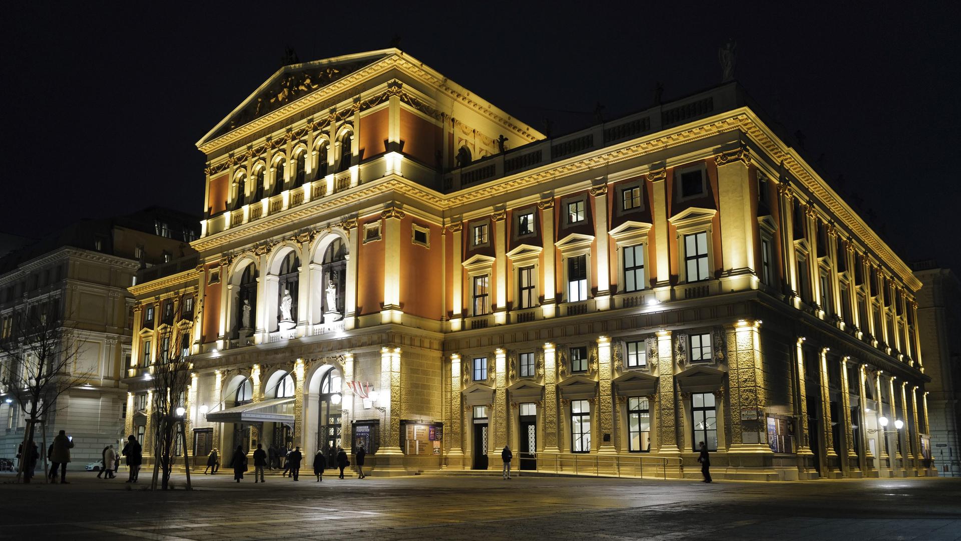 Ein nächtlicher Blick auf den Wiener Musikverein; Menschen betreten das beleuchtete Gebäude. Ein nächtlicher Blick auf den Wiener Musikverein; Menschen betreten das beleuchtete Gebäude.