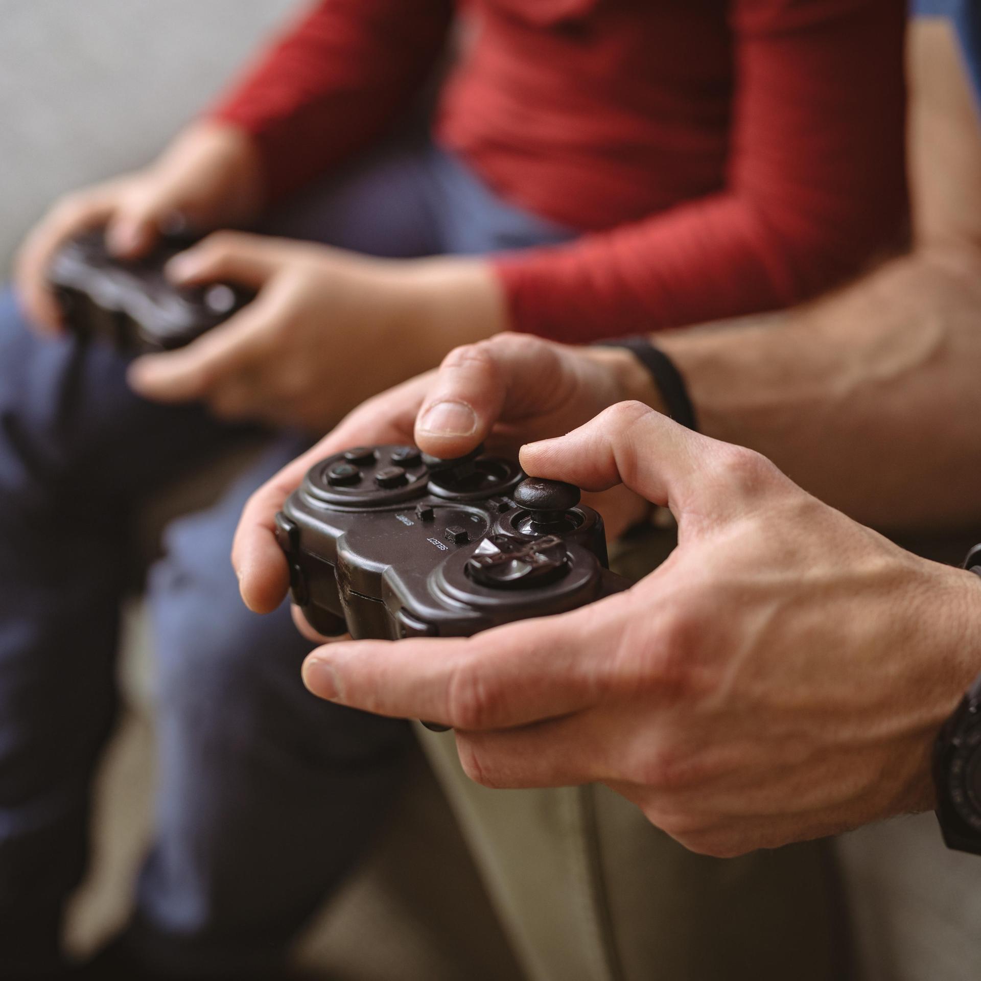 Erwachsenen- und Kinderhände beim gemeinsamen Computerspiel. 