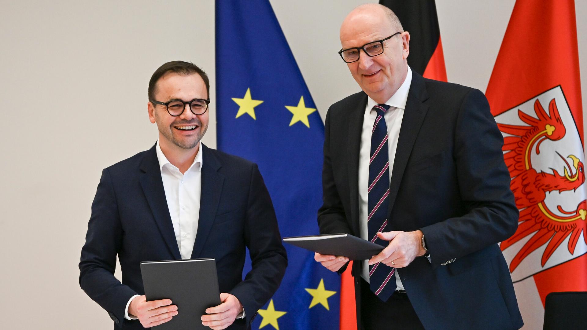 Jan Redmann (l, CDU), Vorsitzender der Brandenburger CDU, und Dietmar Woidke (SPD), Ministerpräsident von Brandenburg, lächeln nach der Unterzeichnung vom Brandenburger Koalitionsvertrag. Jan Redmann (l, CDU), Vorsitzender der Brandenburger CDU, und Dietmar Woidke (SPD), Ministerpräsident von Brandenburg, lächeln nach der Unterzeichnung vom Brandenburger Koalitionsvertrag.