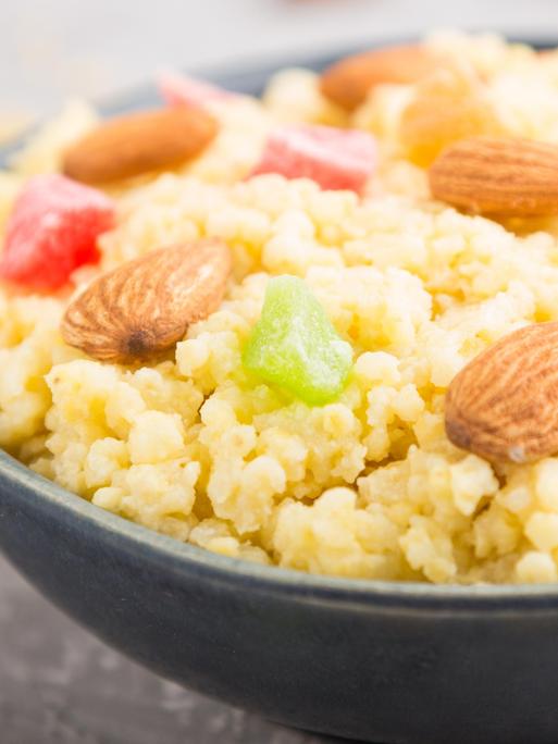 Hirsebrei mit kandierten Früchten und Mandeln in einer Keramikschale
