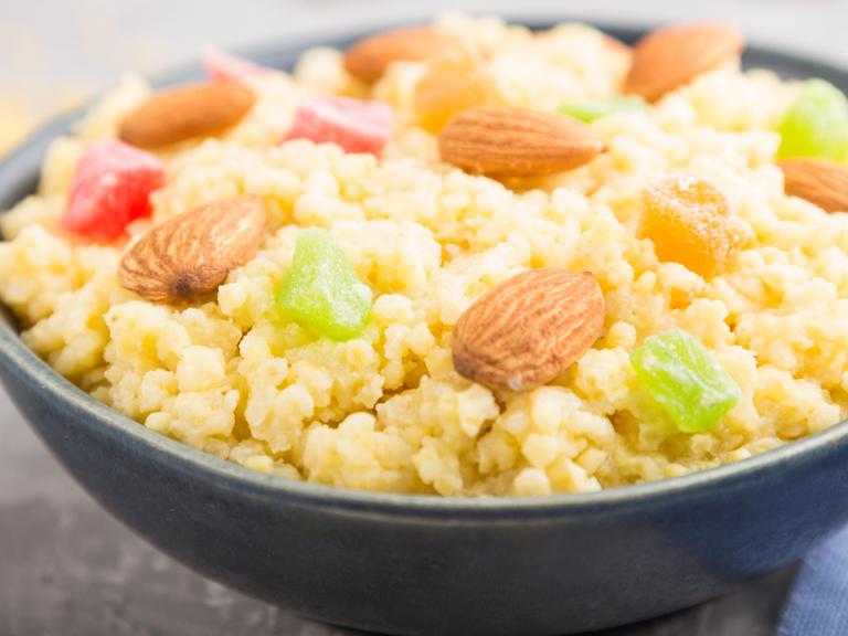 Hirsebrei mit kandierten Früchten und Mandeln in einer Keramikschale
