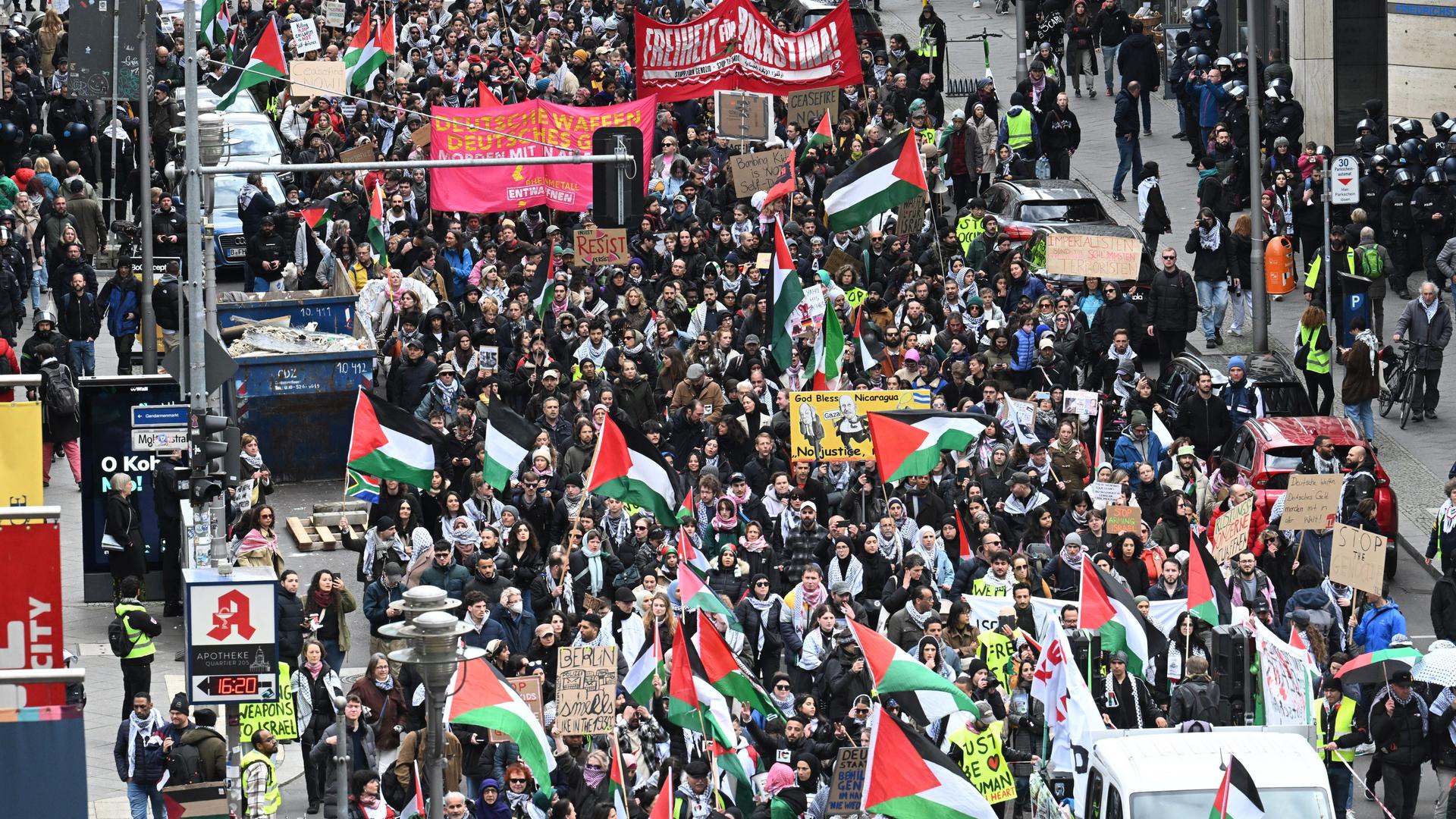 Demonstranten laufen mit Palästinenser-Flaggen und Spruchbändern durch die Berliner Friedrichstrasse.