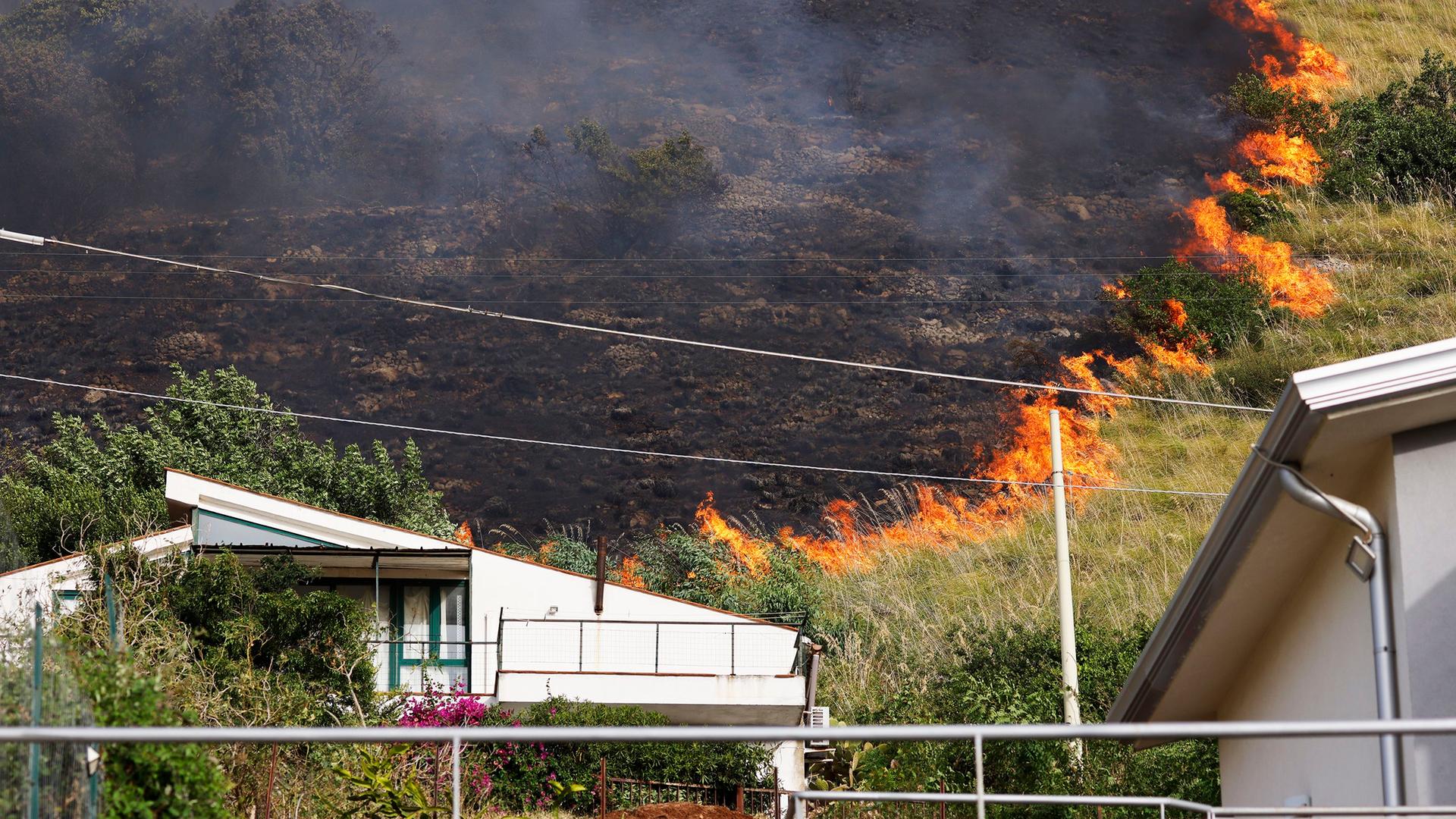 Italien, Capaci: Ein Feuer breitet sich auf einer Fläche hinter einem Wohnhaus in der Nähe von Palermo aus. Italien, Capaci: Ein Feuer breitet sich auf einer Fläche hinter einem Wohnhaus in der Nähe von Palermo aus.