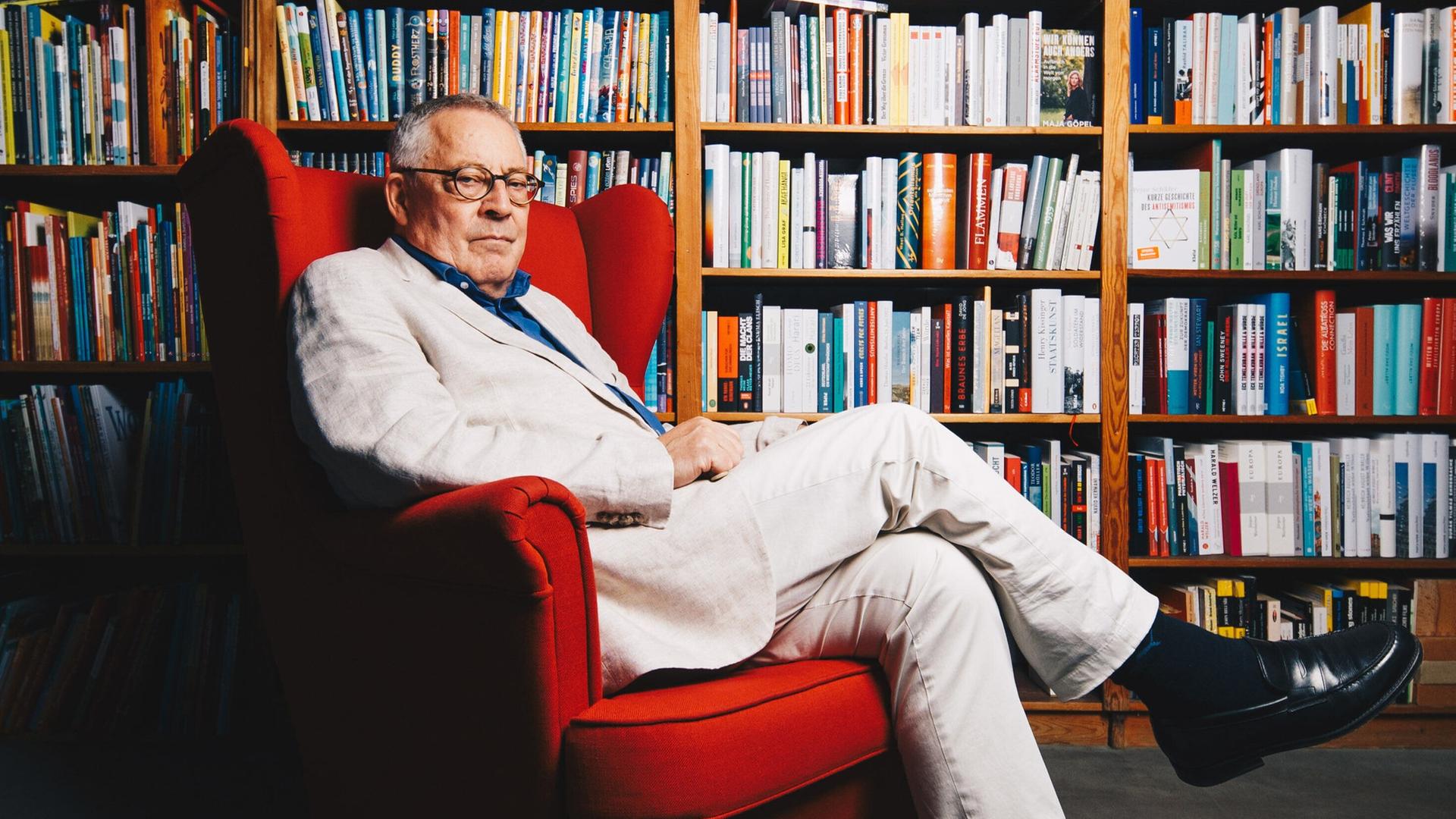 30.09.2022 - Berlin - Der Autor Karl Schlögel posiert in einem roten Sessel vor Bücherregalen in einer Buchhandlung am Bayrischen Platz in Berlin.