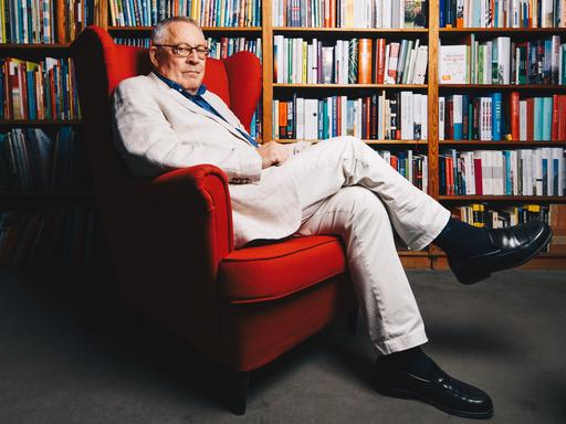 30.09.2022 - Berlin - Der Autor Karl Schlögel posiert in einem roten Sessel vor Bücherregalen in einer Buchhandlung am Bayrischen Platz in Berlin.