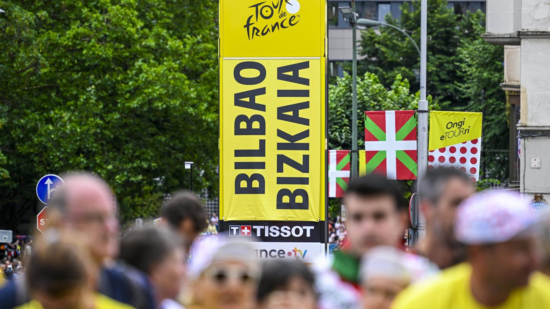 Ein großes Schild mit den Schriftzügen "Bilbao" und "Tour de France" ragt aus einer Menschenmasse hervor. Ein großes Schild mit den Schriftzügen "Bilbao" und "Tour de France" ragt aus einer Menschenmasse hervor.