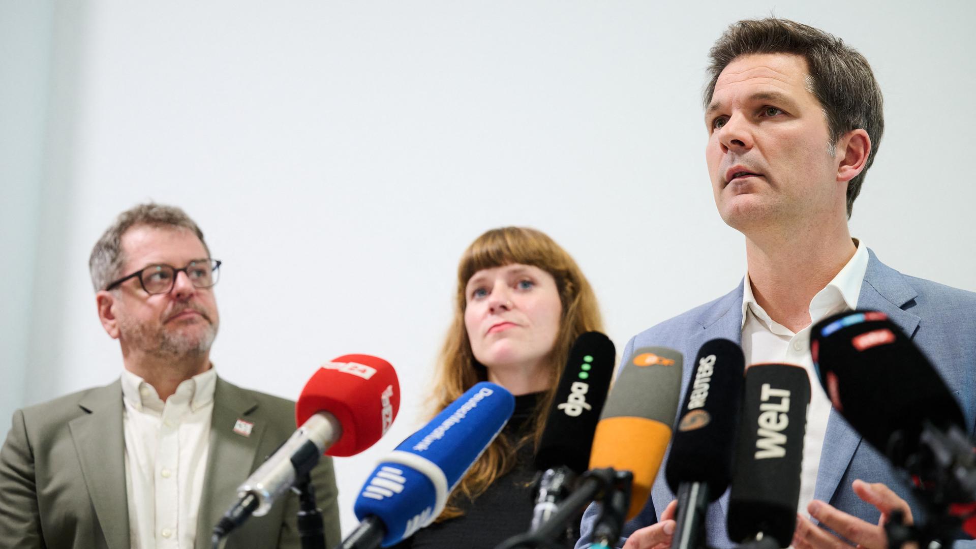 Steffen Krach (r-l, SPD), Kerstin Wolter (Die Linke) und Werner Graf (Bündnis90/Die Grünen) stehen hinter Mikrofonen. 