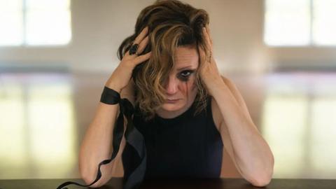 Nina Nastasia auf einen Tisch gebeugt mit verheultem Makup
