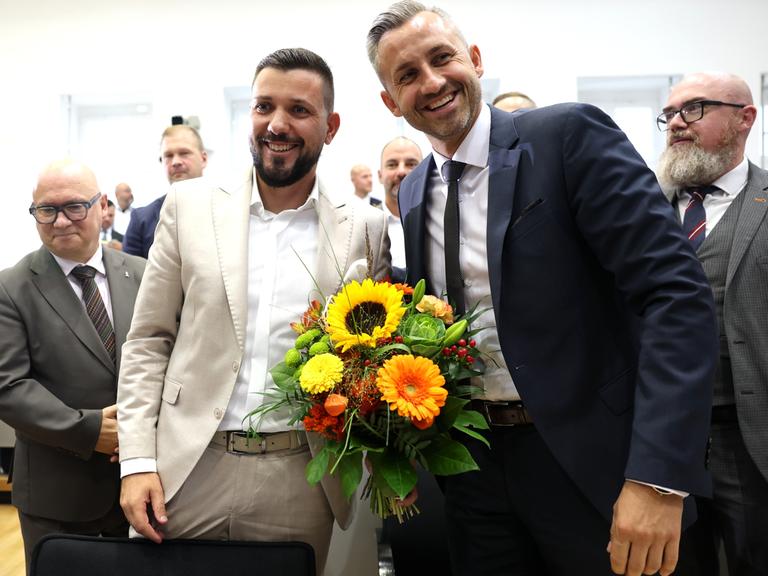 AfD-Spitzenvertreter gratulieren Tobias Rausch zur Wahl zum Landtagspräsidenten während der konstituierenden Sitzung des Landtags von Sachsen-Anhalt. Rausch und Siegmund (Mitte) halten einen gelben Blumenstrauß.