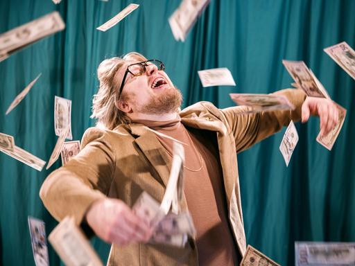 Ein Mann steht inmitten vom Himmel fallender Geldscheine und freut sich.