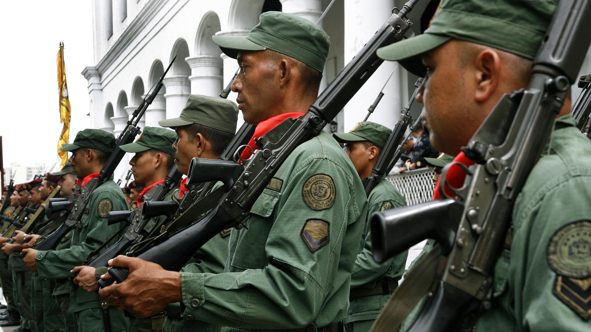 Reservisten, junge Rekruten der venezolanischen Armee und Freiwillige stehen mit Gewehren über der Schulter vor einem Gebäude und haben sich zu einem Militärtraining eingefunden.  