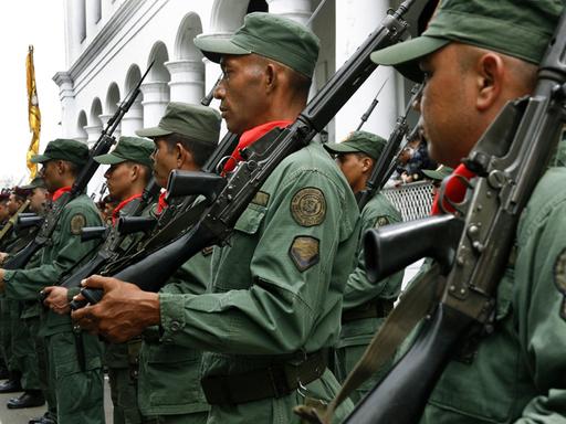 Reservisten, junge Rekruten der venezolanischen Armee und Freiwillige stehen mit Gewehren über der Schulter vor einem Gebäude und haben sich zu einem Militärtraining eingefunden.  