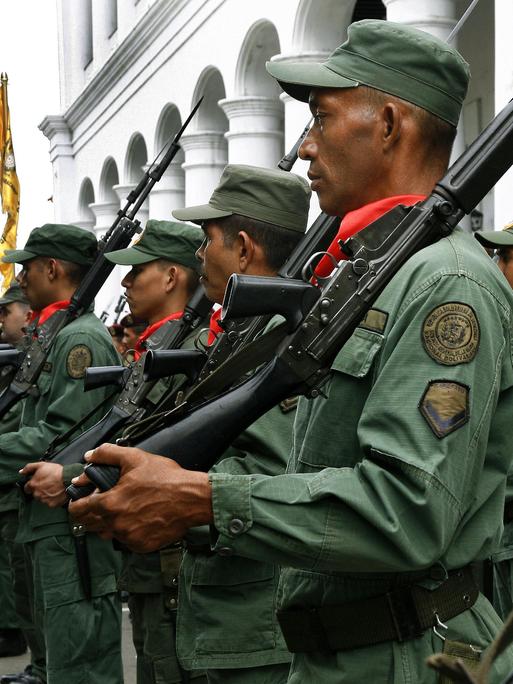 Reservisten, junge Rekruten der venezolanischen Armee und Freiwillige stehen mit Gewehren über der Schulter vor einem Gebäude und haben sich zu einem Militärtraining eingefunden.  
