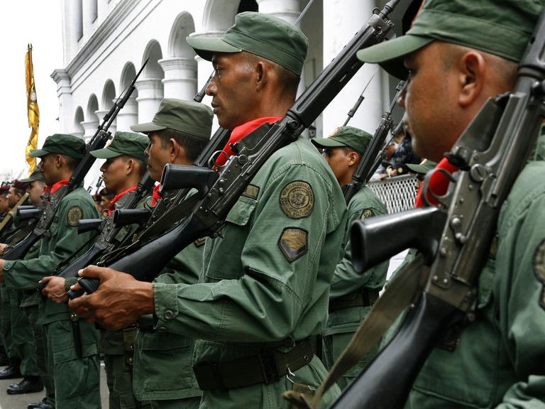 Reservisten, junge Rekruten der venezolanischen Armee und Freiwillige stehen mit Gewehren über der Schulter vor einem Gebäude und haben sich zu einem Militärtraining eingefunden.  