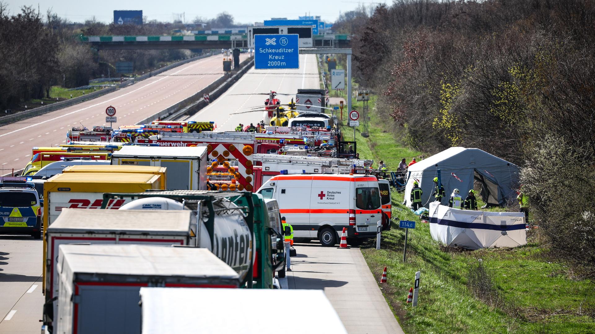 Einsatzfahrzeuge und Rettungshubschrauber stehen auf der A9 an der Unfallstelle.