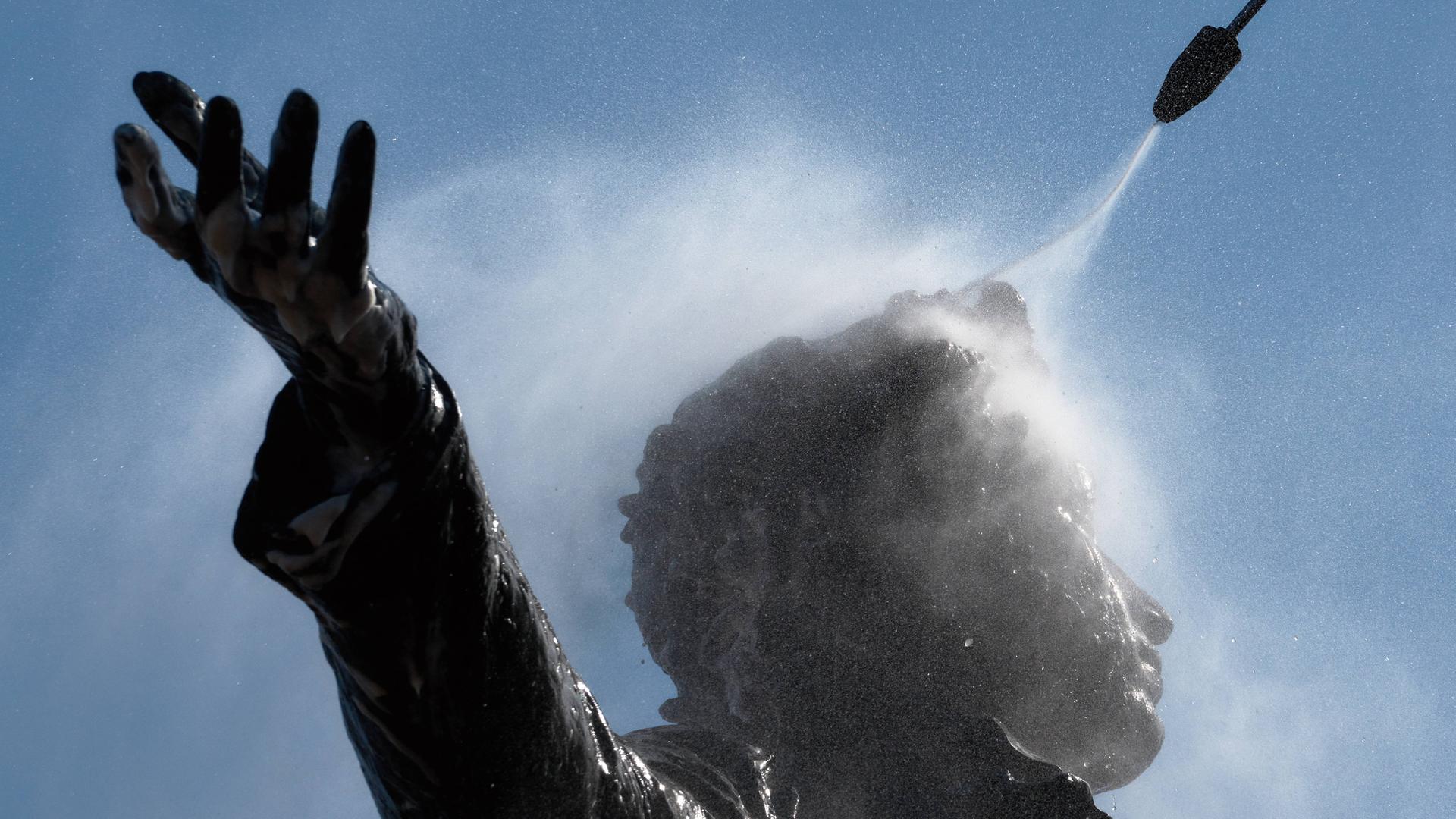 Ein Denkmal für den russischen Dichter Alexander Puschkin wird von einem Stadtarbeiter mit einem Wasserstrahl abgespritzt und gereinigt. 