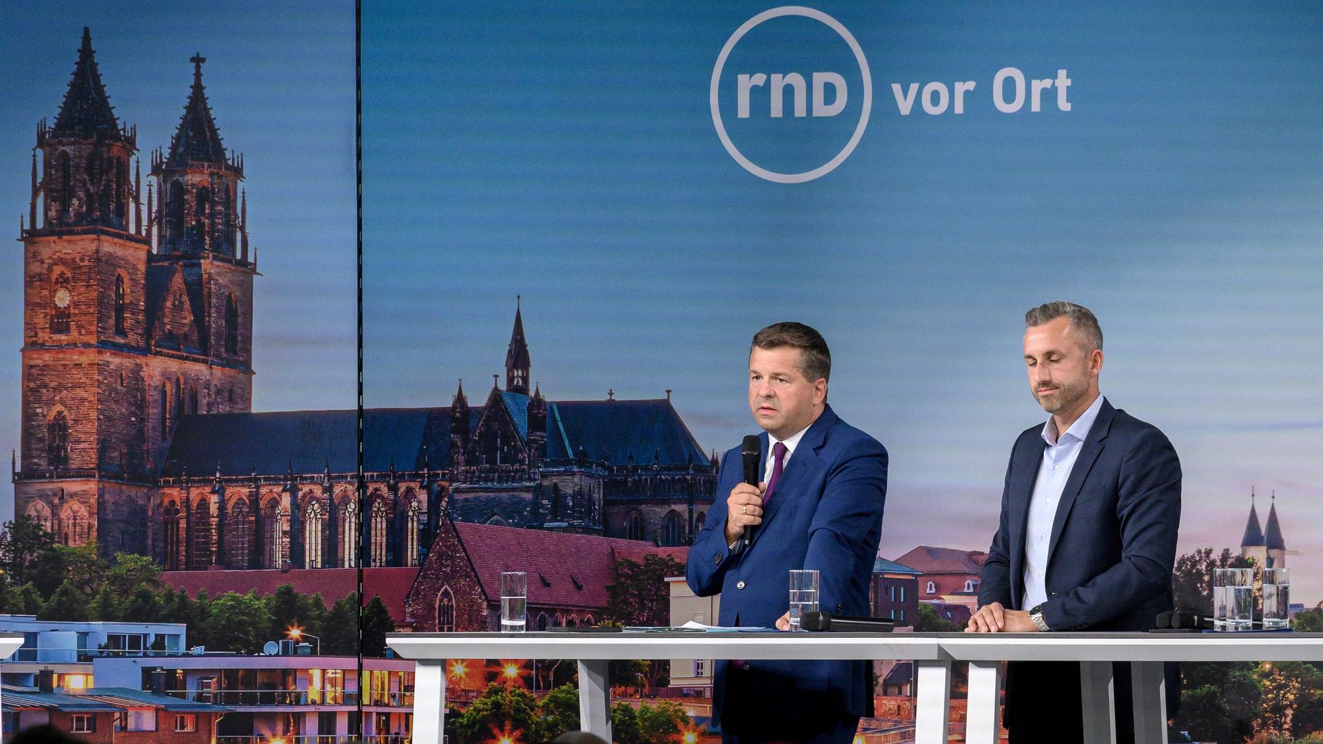 Sven Schulze (l, CDU), Ministerpräsident von Sachsen-Anhalt und Ulrich Siegmund (AfD) stehen in der Hyparschale in Magdeburg auf der Bühne. 