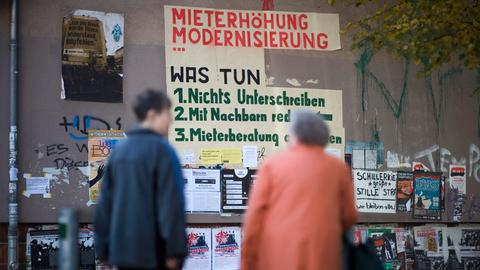 Zwei Bewohner schauen auf ein Graffiti zur Mieterhöhung im Schillerkiez in Berlin-Neukölln. Es dient als Protest gegen die Zunahme von touristischen Kurzzeitmieten, gegen steigende Kosten und Verdrängung. 