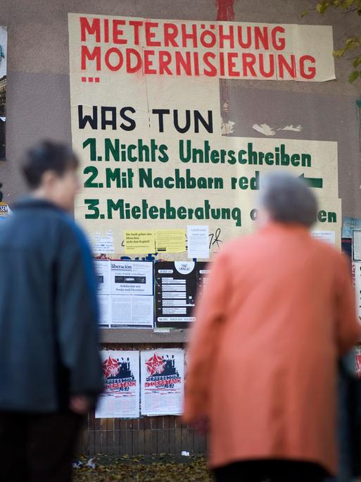Zwei Bewohner schauen auf ein Graffiti zur Mieterhöhung im Schillerkiez in Berlin-Neukölln. Es dient als Protest gegen die Zunahme von touristischen Kurzzeitmieten, gegen steigende Kosten und Verdrängung. 