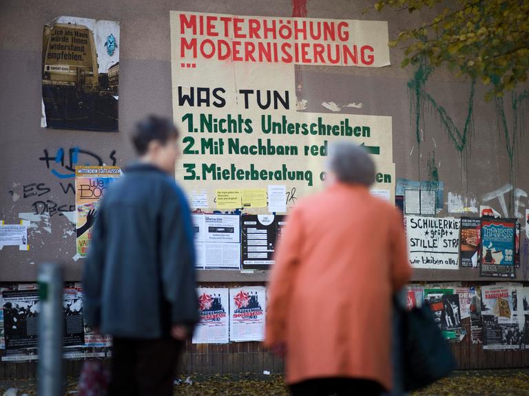 Zwei Bewohner schauen auf ein Graffiti zur Mieterhöhung im Schillerkiez in Berlin-Neukölln. Es dient als Protest gegen die Zunahme von touristischen Kurzzeitmieten, gegen steigende Kosten und Verdrängung. 