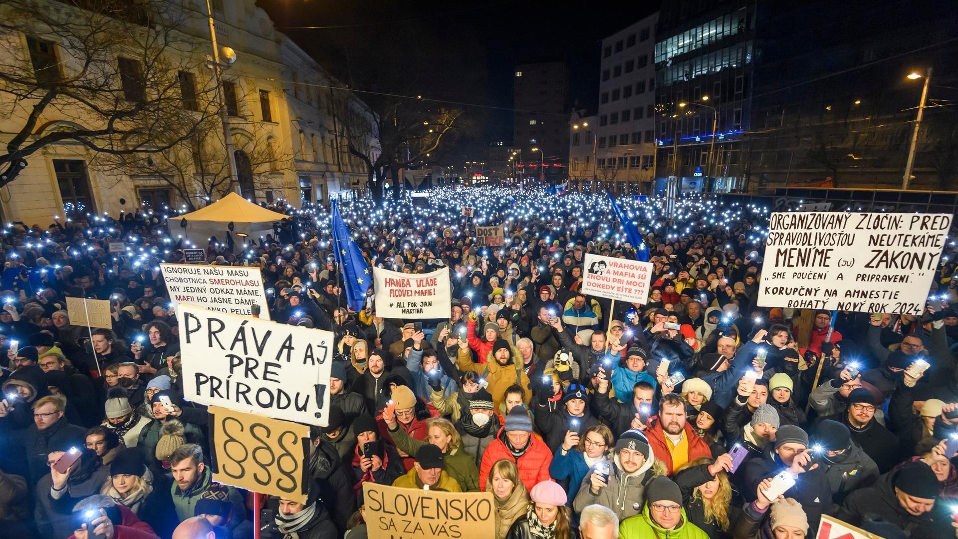 Blick von vorne auf die große Menge an Demonstranten mit Transprarenten. Es ist dunkel, viele Menschen leuchten mit ihren Handys. Blick von vorne auf die große Menge an Demonstranten mit Transprarenten. Es ist dunkel, viele Menschen leuchten mit ihren Handys.
