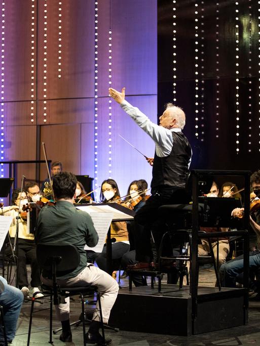 Mit vereinten Kräften: Dirigent Daniel Barenboim mit seinem Orchester zum Beethoven-Geburtstag 2020 in Bonn. Daniel Barenboim steht auf einem Pult in der Mitte und dirigiert, um ihn herum seine Symphoniker. 