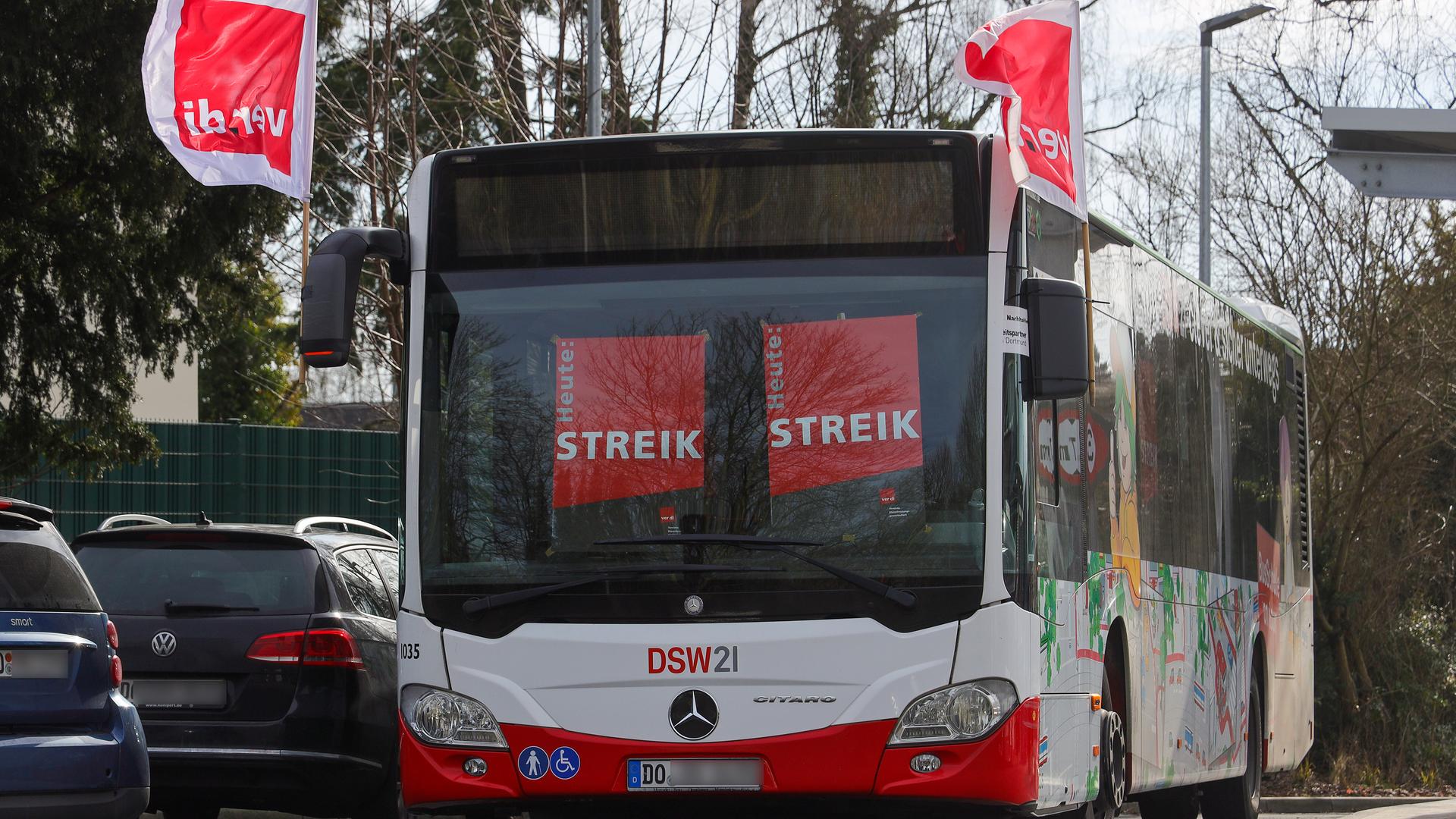 Ein leerer Bus steht auf einem Parkplatz. Hinter den Scheiben hängen Schilder mit der Aufschrift "Streik".