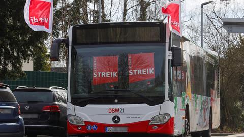 Ein leerer Bus steht auf einem Parkplatz. Hinter den Scheiben hängen Schilder mit der Aufschrift "Streik".
