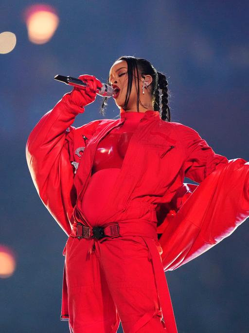 Die Sängerin Rihanna bei ihrem Auftritt. Sie ist ganz in rot gekleidet und man sieht deutlich ihren Babybauch.