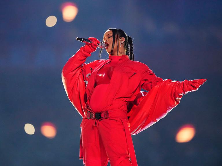 Die Sängerin Rihanna bei ihrem Auftritt. Sie ist ganz in rot gekleidet und man sieht deutlich ihren Babybauch.