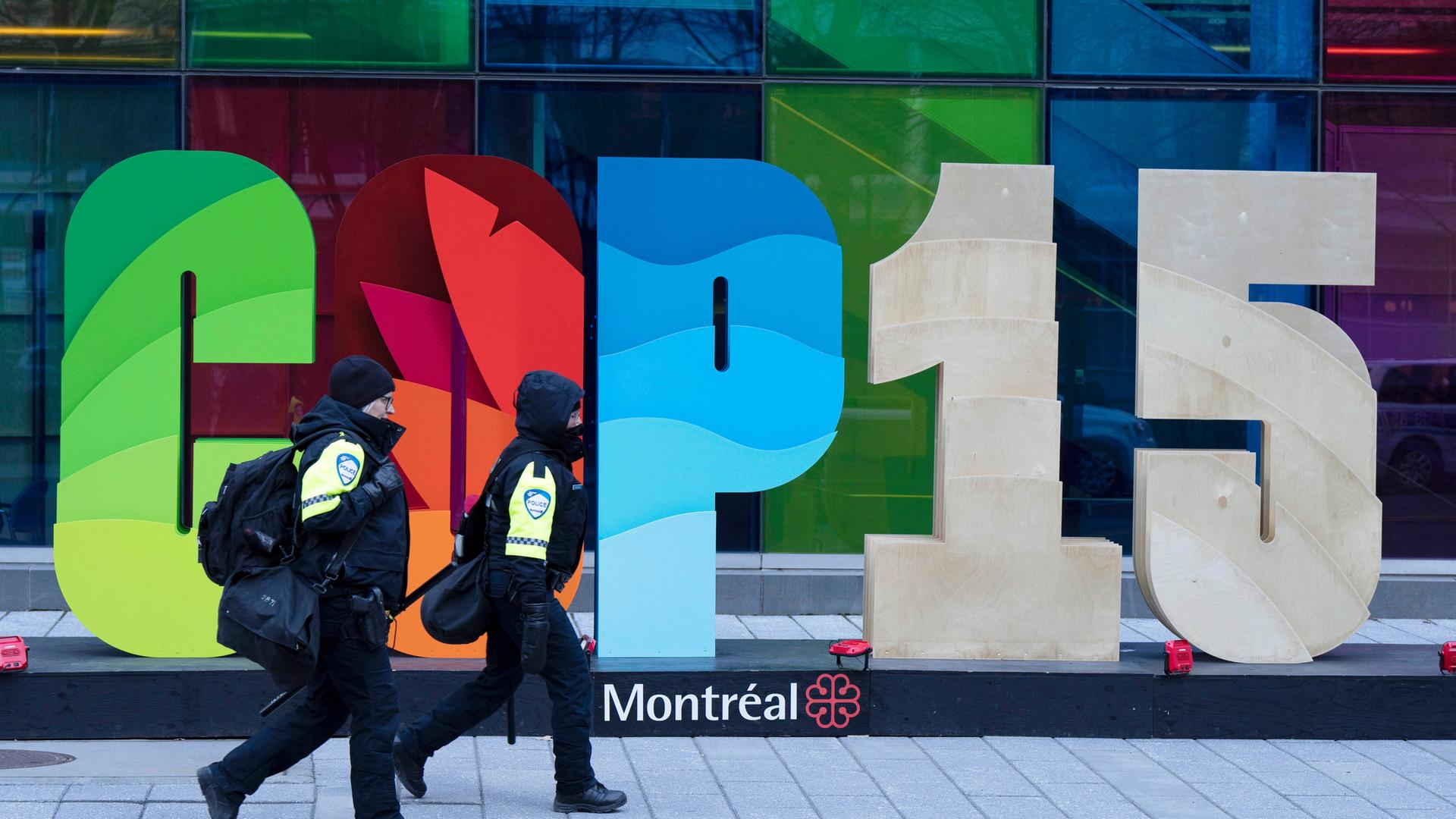 Polizisten gehen am 14.12.2022 am Schriftzug "COP15" bei der Biodiversitätskonferenz in Montreal vorbei 