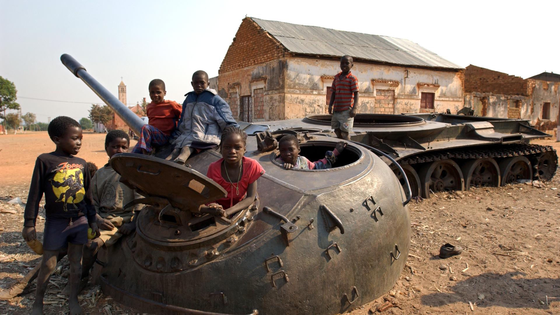 Ein auf eine Mine gefahrener Panzer dient den Kindern 2003 in dem Dörfchen Kunje nahe der völlig zerschossenen Provinzhauptstadt Kuito 2003 als Spielgerät